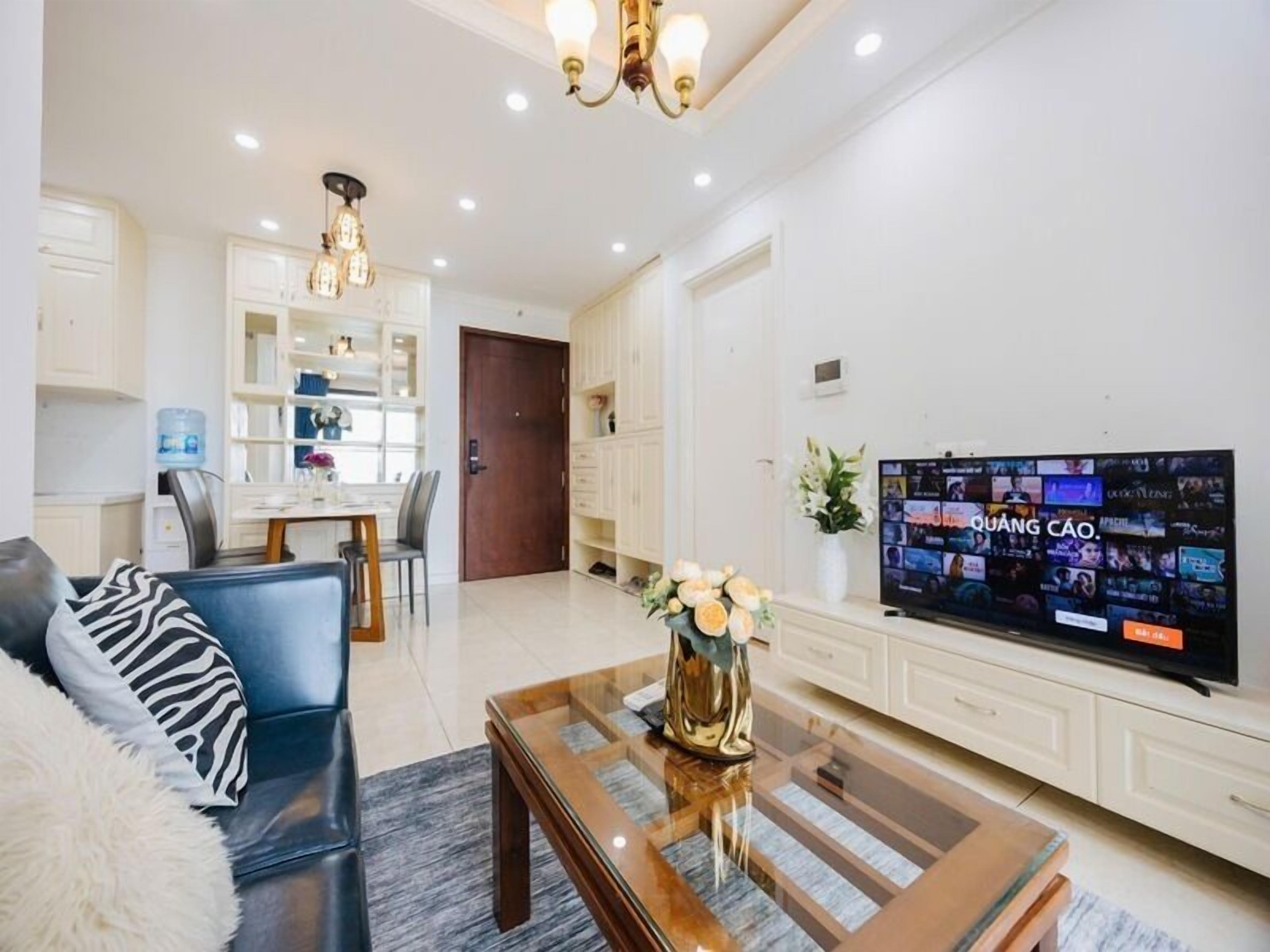 Een moderne woonkamer met een bank, salontafel, televisie en een eethoek met stoelen en een tafel.