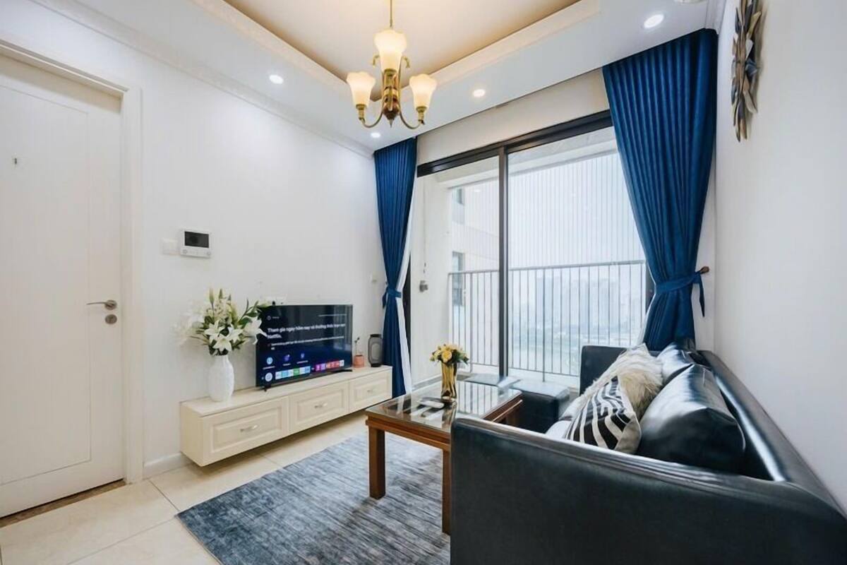 A modern living room with a black sofa, a coffee table, and a TV on a white cabinet.