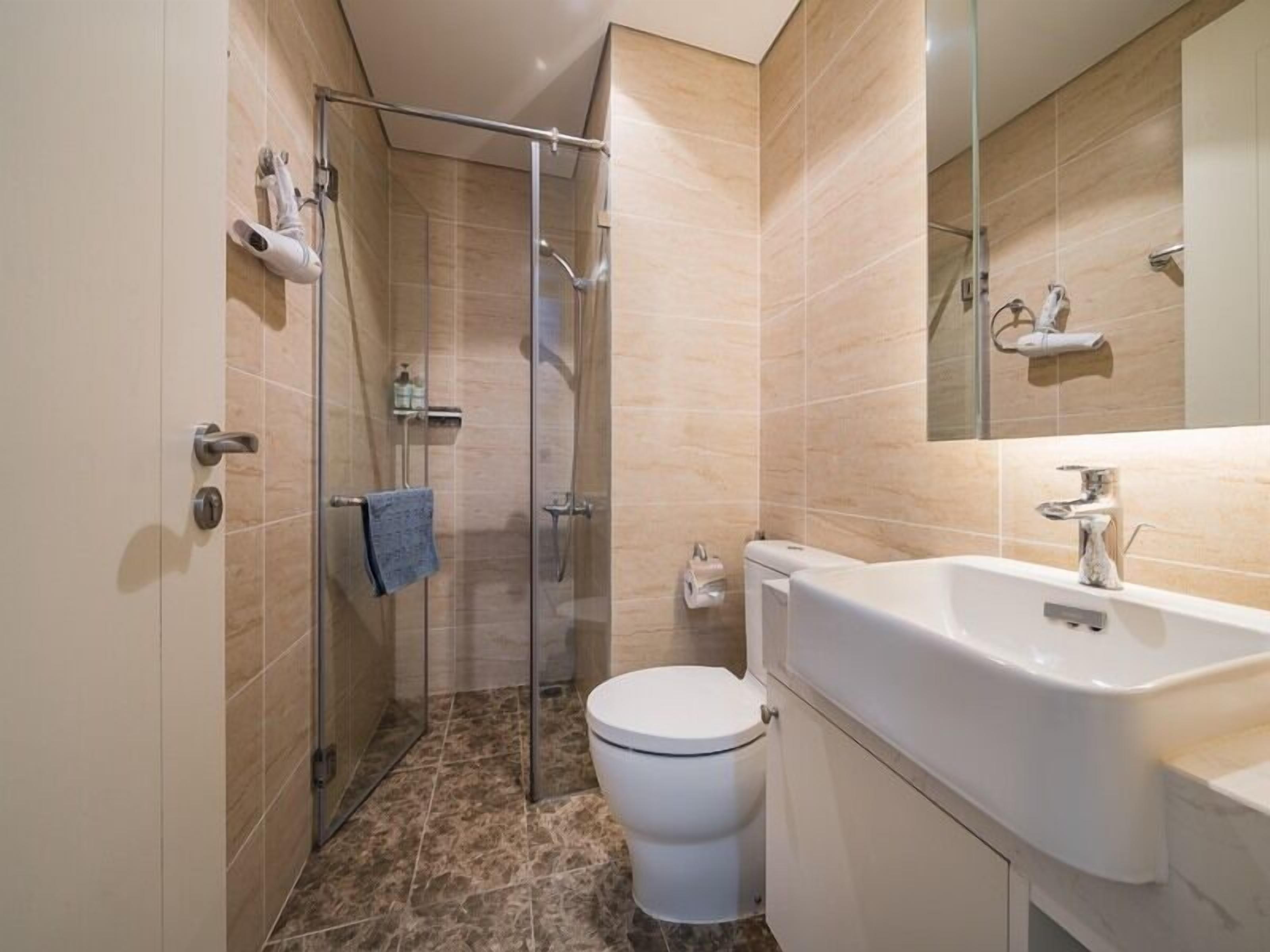 A modern bathroom with a glass shower enclosure, a white toilet, and a large sink.