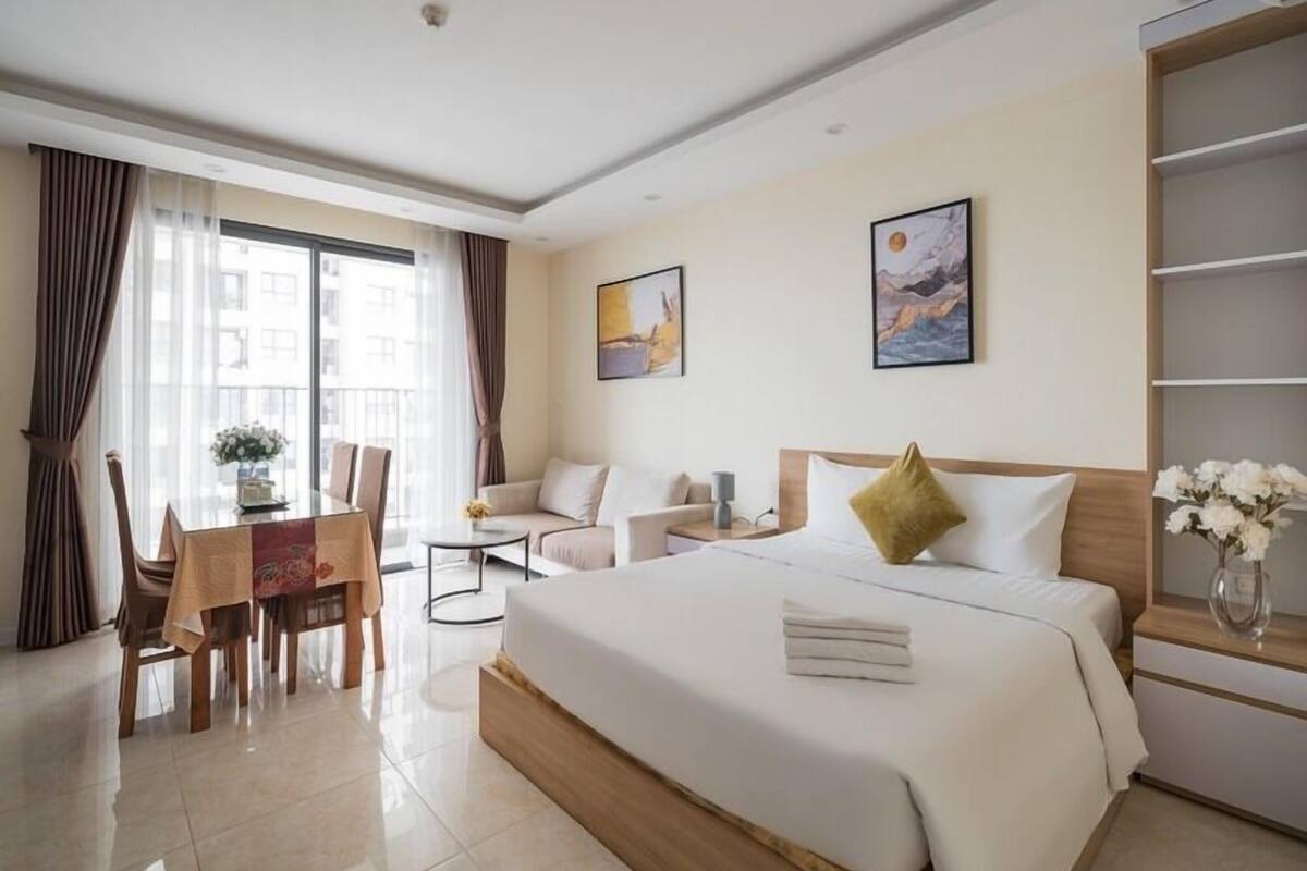 A hotel room with a bed, a desk, a chair, a sofa, and a large window.