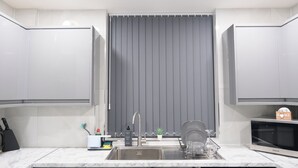 A modern kitchen with white cabinets, a grey backsplash, a stainless steel sink, and a built-in microwave. - Modern House - 3 Bedrooms - 1 Bath - ManCity (Manchester)