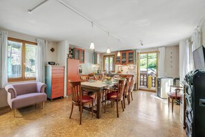 Eine geräumige Küche mit Holzausstattung, einem Esstisch und Stühlen. Im Wohnbereich befindet sich eine Couch und ein Fernseher.
