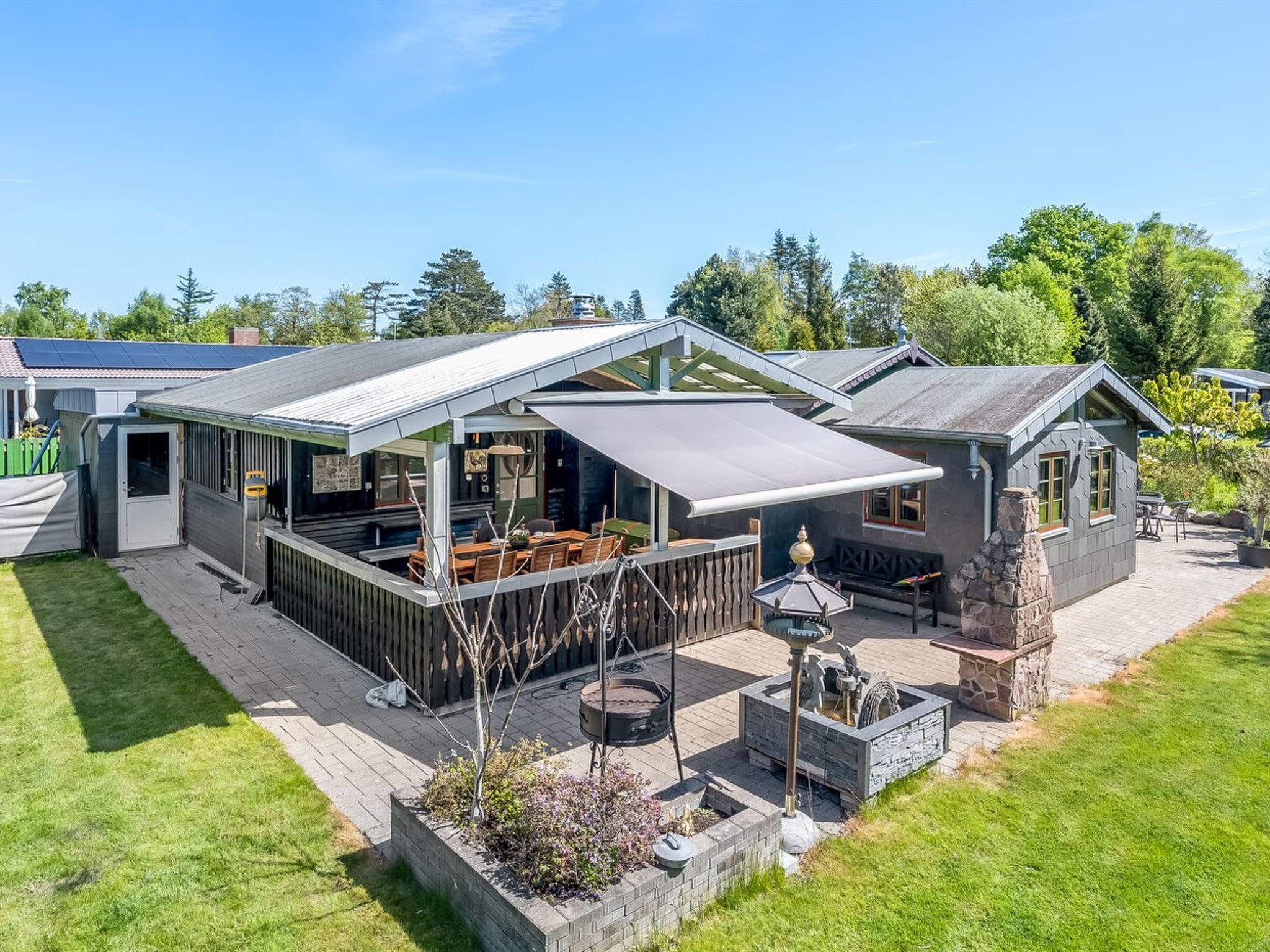 A modern house with a patio, outdoor seating, and a stone fireplace.