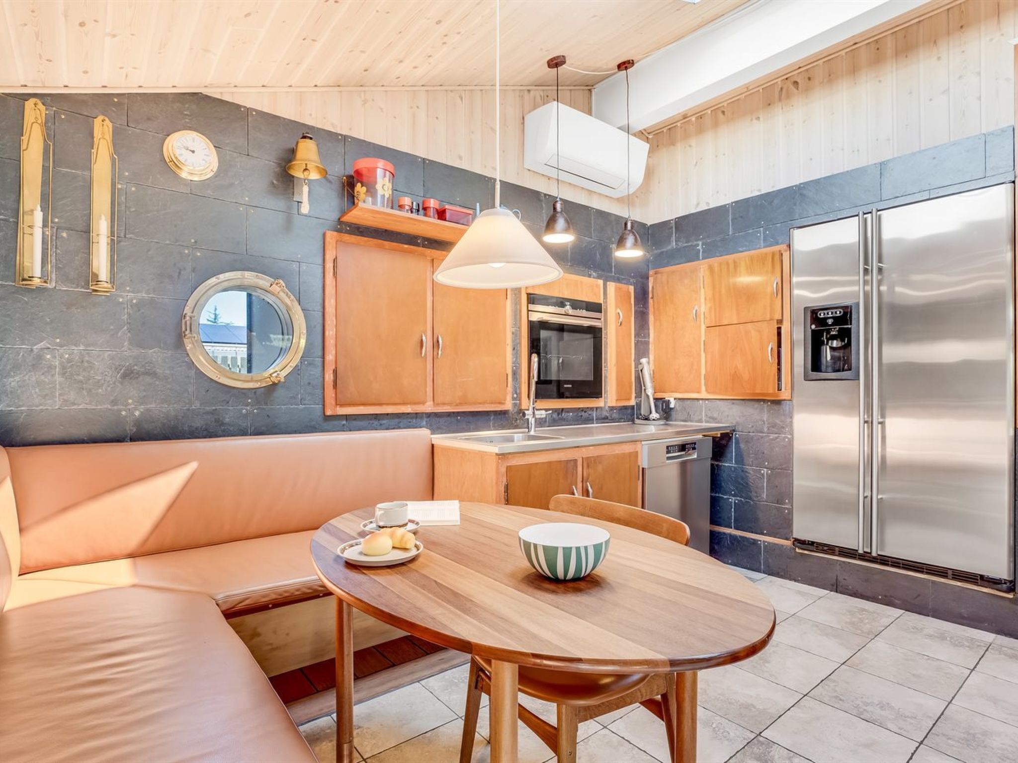 A modern kitchen with a wooden bench, a round dining table, and stainless steel appliances.