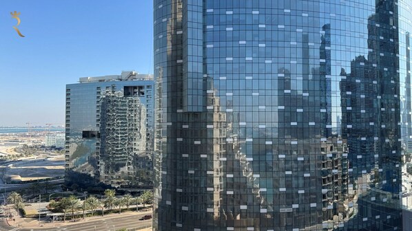 Un edificio alto con fachada de vidrio reflectante, rodeado de otros edificios y un cielo despejado.