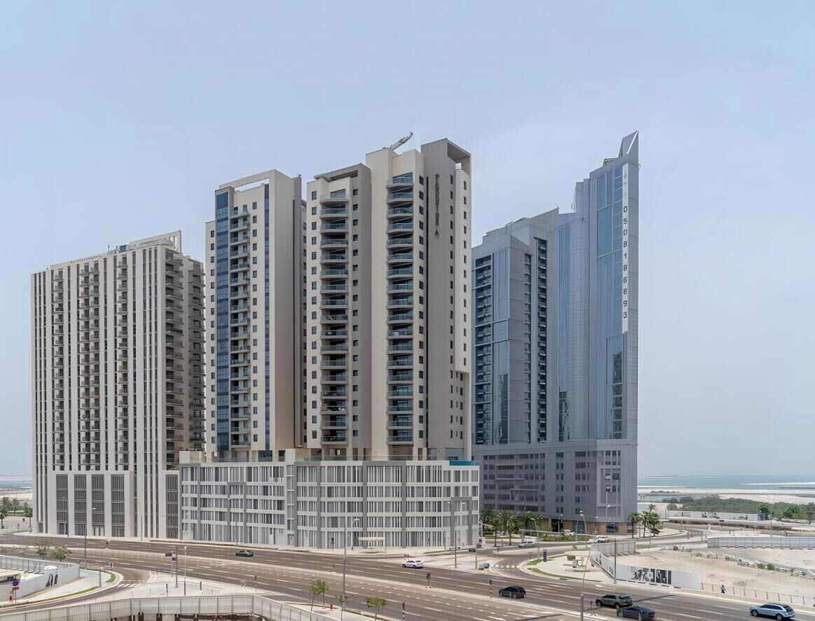A high-rise residential building with multiple floors, a central courtyard, and a view of the coastline.