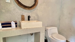 A bathroom with a wooden-framed mirror, a beige sink, a white toilet, and a wooden floor. - Cinze Villas and Hot Spring (Kintamani)