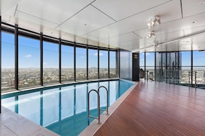 A modern indoor pool with large windows and a city view.