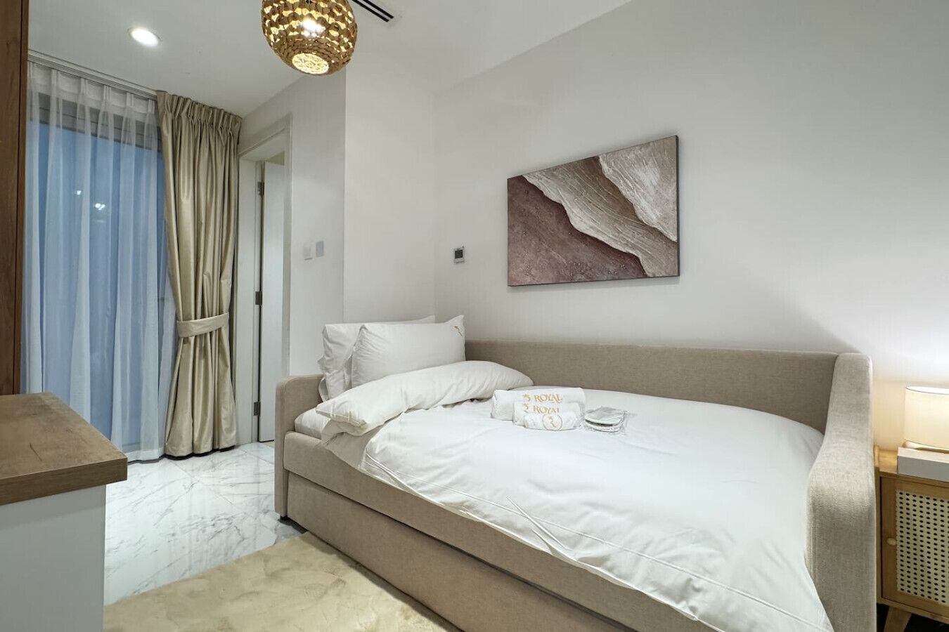 Ein Schlafzimmer mit Bett, Vorhängen, einem Wandbild und einem Nachttisch.