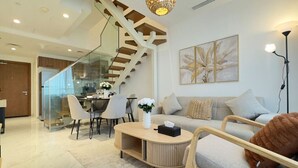 Un salon moderne avec un escalier, un coin repas et un canapé agrémenté d’un coussin décoratif.