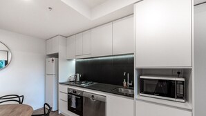 Une cuisine moderne avec des meubles blancs, un four à micro-ondes encastré, un lave-vaisselle et une cuisinière.