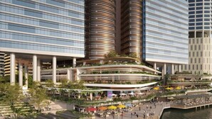 Um moderno empreendimento urbano com uma estrutura cilíndrica central, rodeada por edifícios altos.