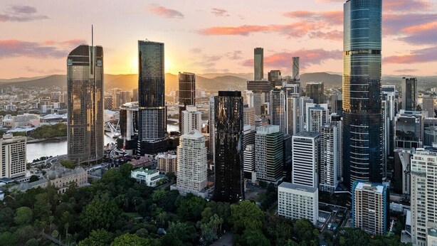 Paisagem urbana com arranha-céus modernos, um rio e um pôr do sol.