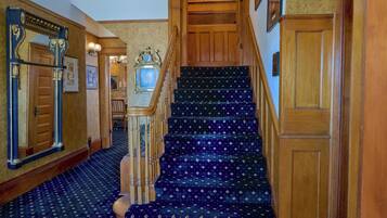 A grand staircase with ornate woodwork and patterned carpet.