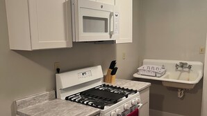 A kitchen with white cabinets, a microwave, a stove, and a sink.