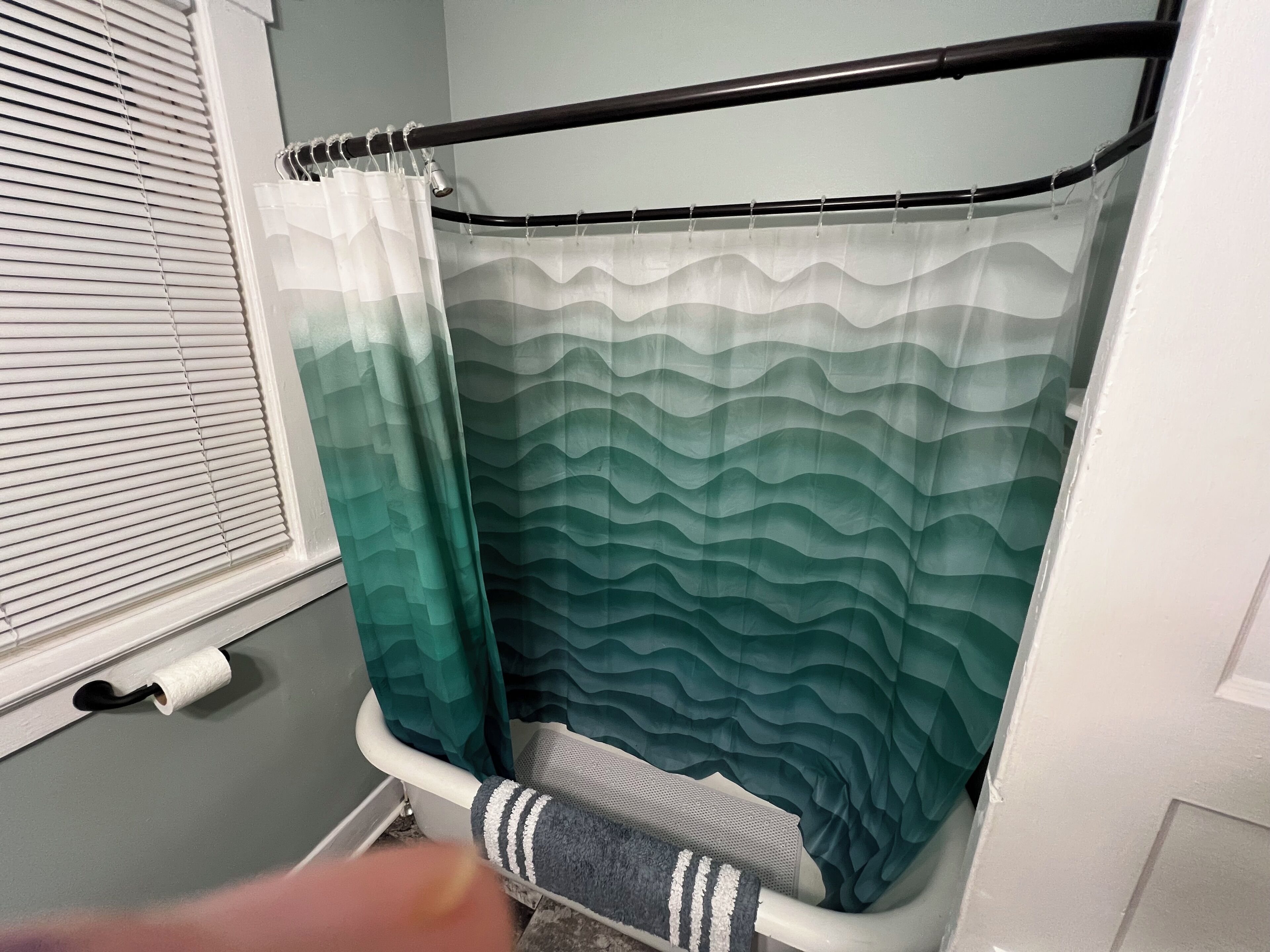 A bathroom with a shower curtain, a towel rack, and a toilet.