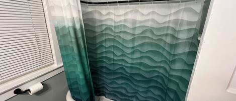 A bathroom with a shower curtain, a towel rack, and a toilet.