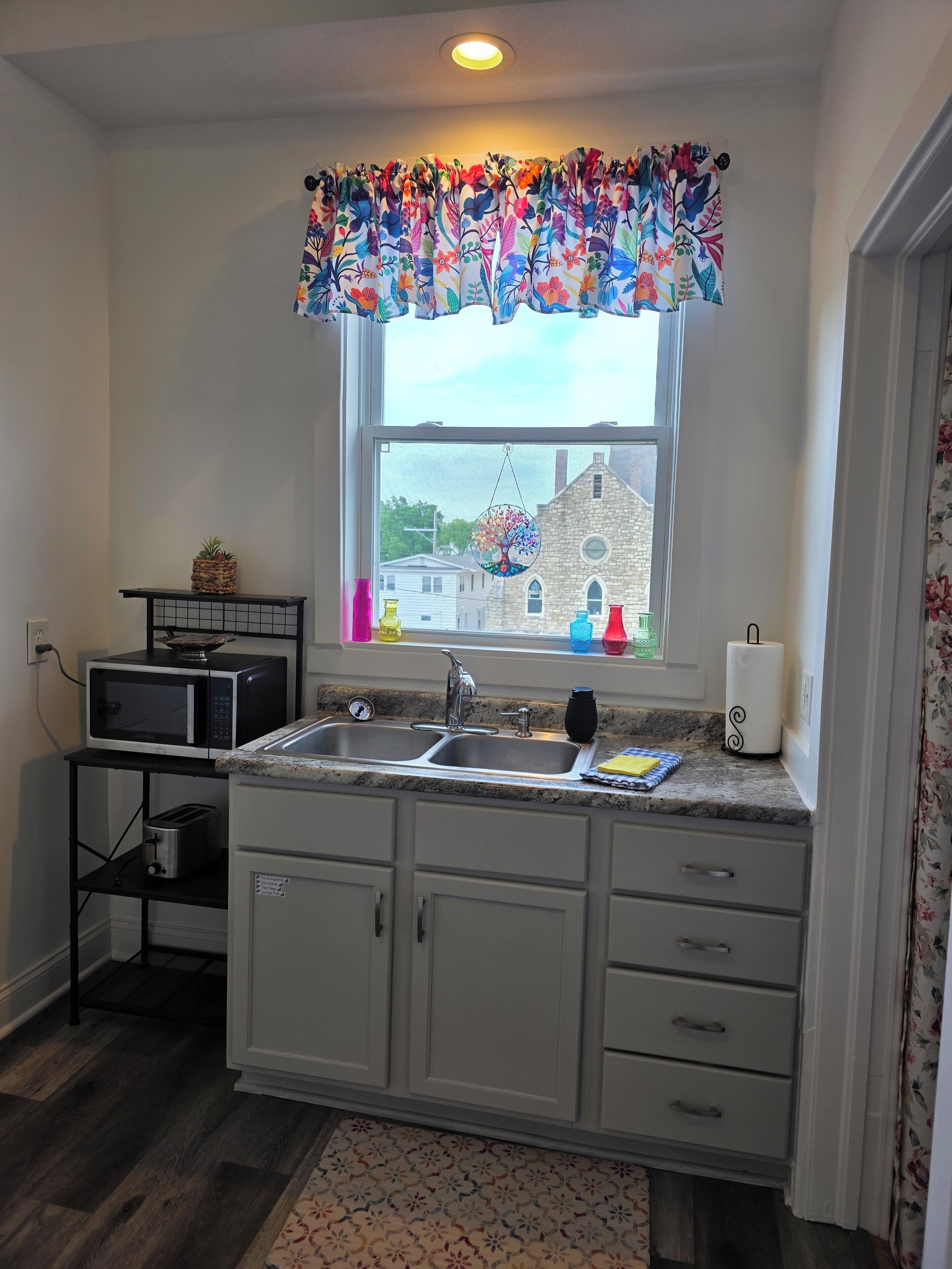 Una cocina con ventana, microondas, tostadora y lavabo.