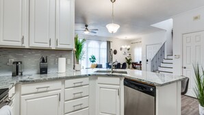 A modern kitchen with white cabinetry, a granite countertop, and a dishwasher. There is a ceiling fan and a chandelier. - Charming 3-bedroom townhome with WiFi,AC in fabulous Frisco. Home away from home (Frisco)
