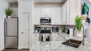 A modern kitchen with white cabinets, stainless steel appliances, and a granite countertop. - Charming 3-bedroom townhome with WiFi,AC in fabulous Frisco. Home away from home (Frisco)