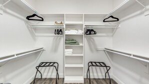 A walk-in closet with white shelving, a central folding shelf, and two metal drying racks. - Charming 3-bedroom townhome with WiFi,AC in fabulous Frisco. Home away from home (Frisco)