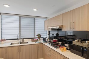 A modern kitchen with wooden cabinets, a stainless steel sink, and a built-in stove. - Dos Camas KING Size en Centro Historico DGO (Durango)