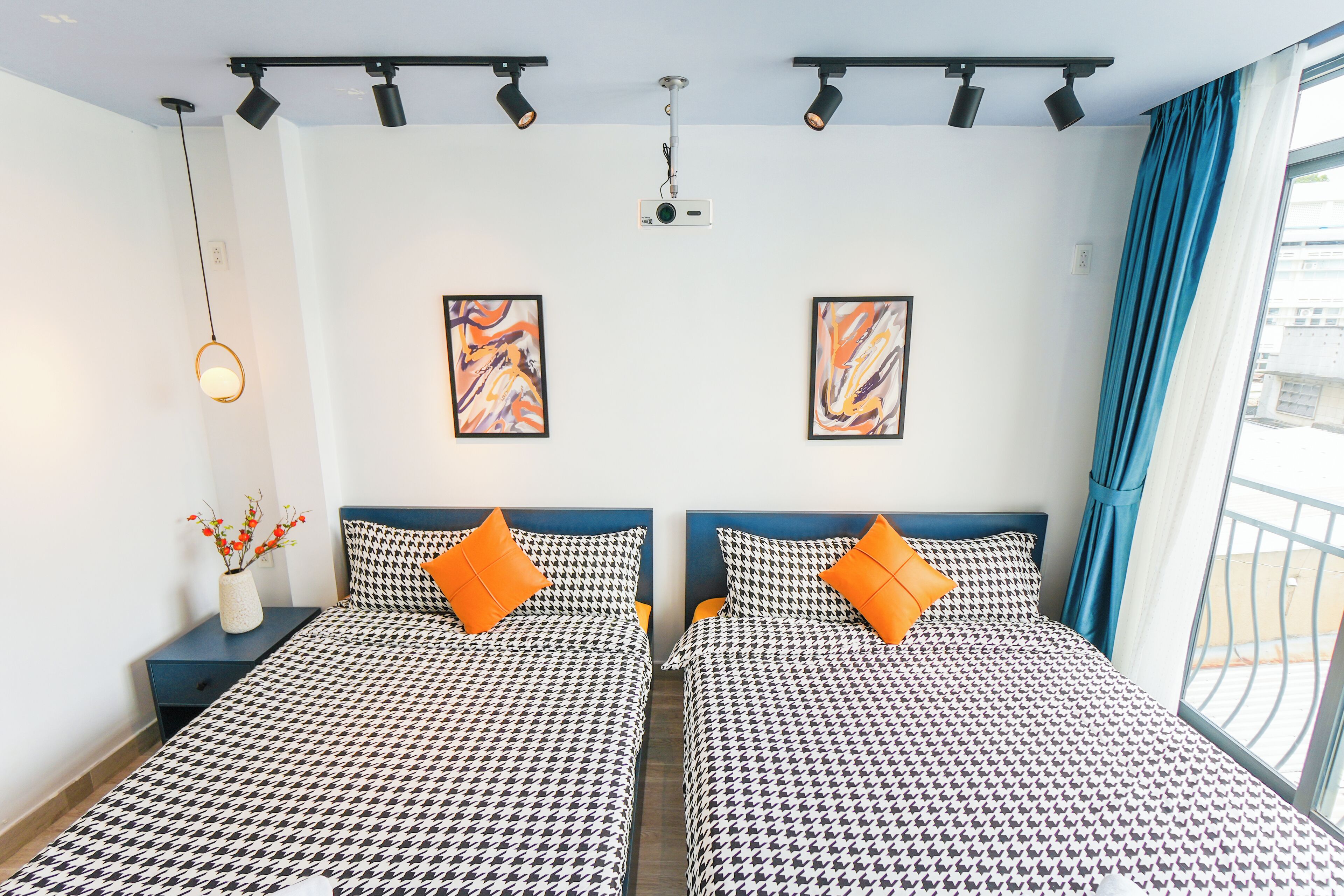 A hotel room with two beds, a projector, and artwork on the walls.