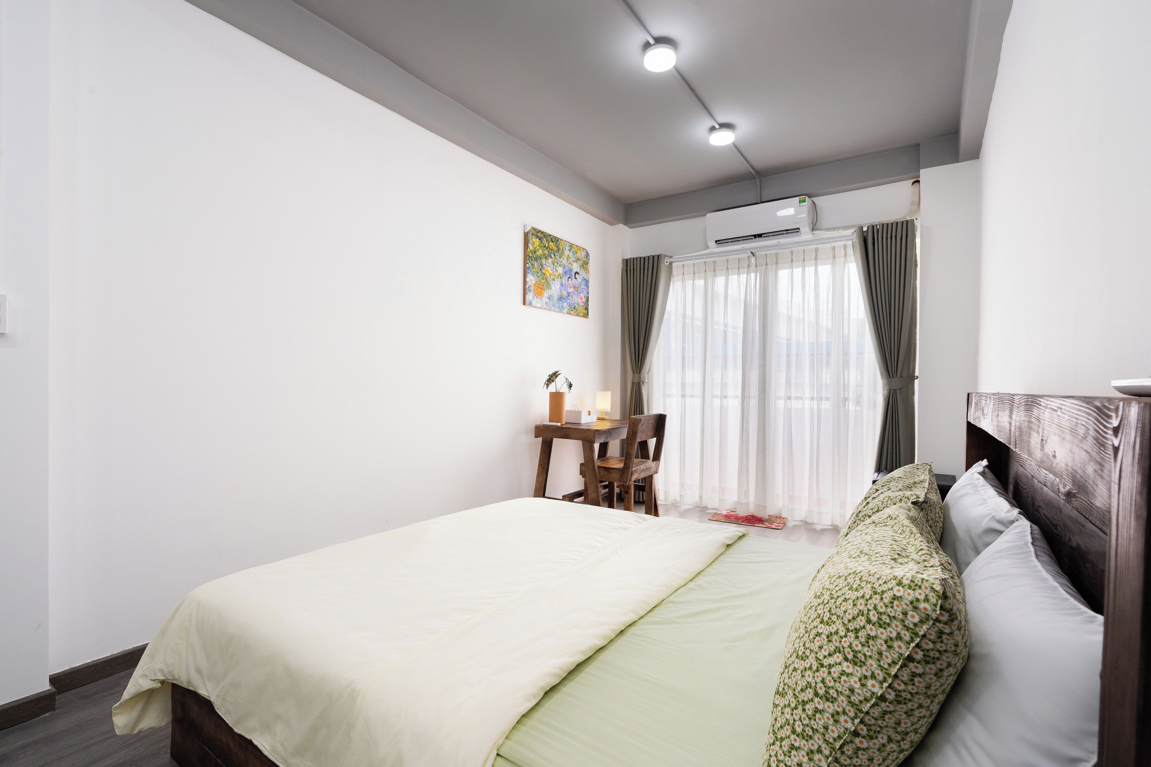 Ein Schlafzimmer mit einem Bett, einem Schreibtisch und einem Stuhl. An der Wand befindet sich eine Klimaanlage.