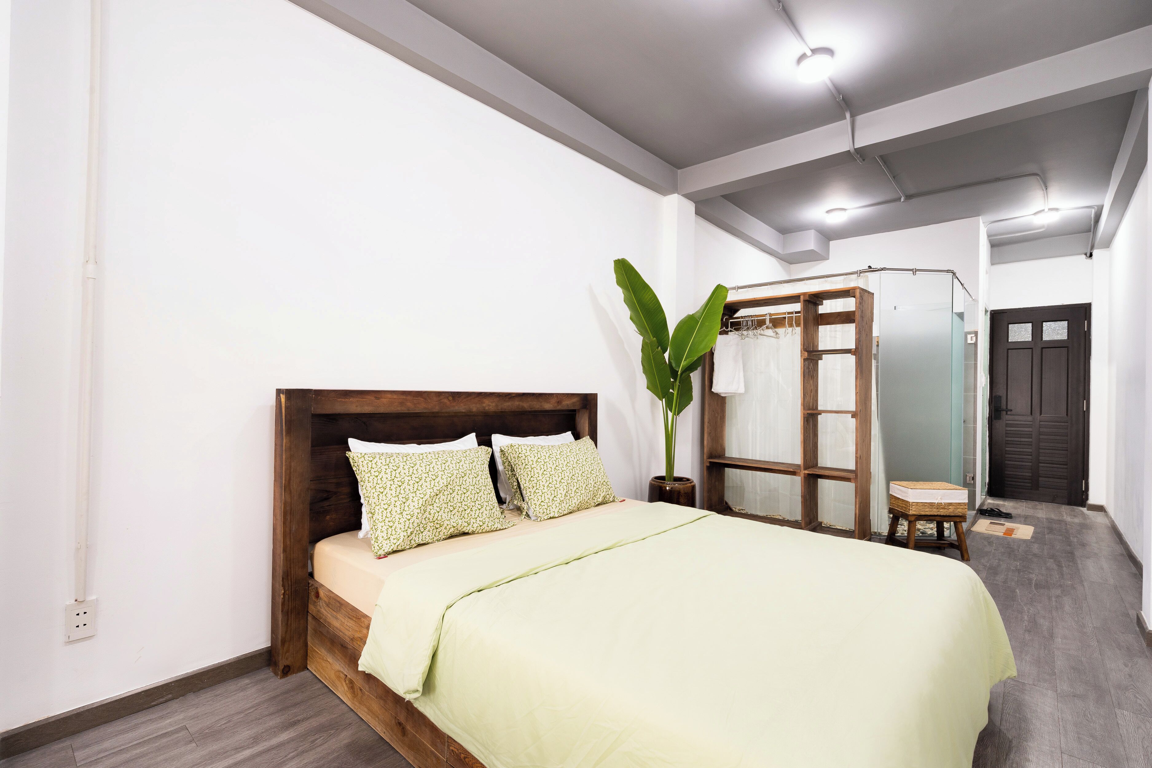 A bedroom with a wooden bed, a potted plant, and a wardrobe.