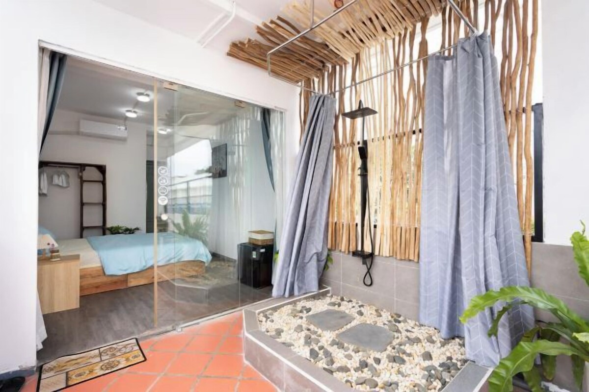 A modern bathroom with a glass shower enclosure, a bamboo curtain, and a small pebble-tiled area.
