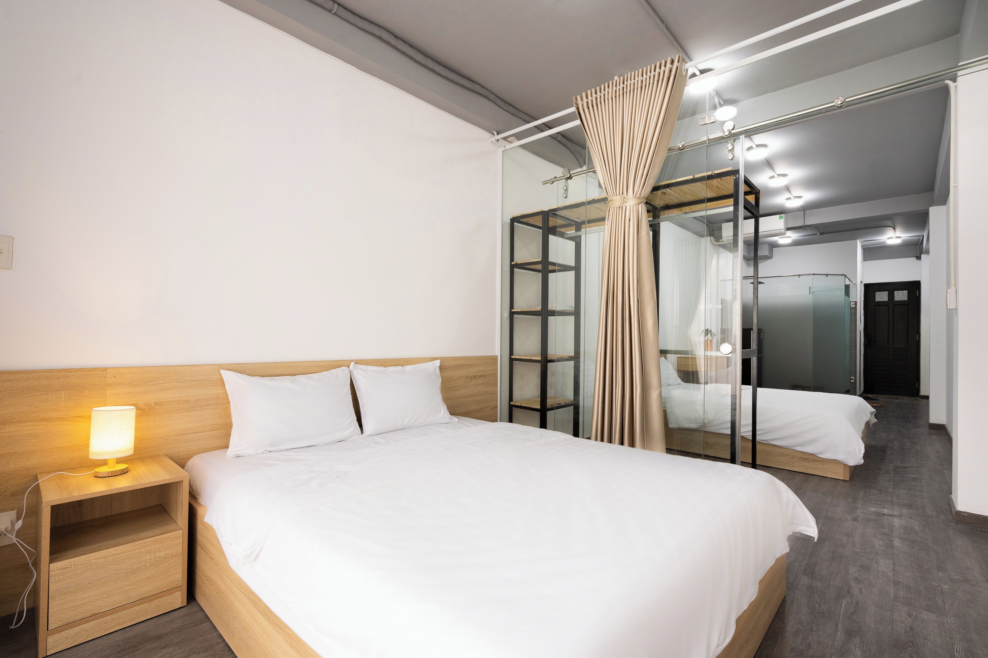 A hotel room with a large bed, a bedside table with a lamp, a mirror, and a wardrobe.