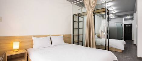 A hotel room with a large bed, a bedside table with a lamp, a mirror, and a wardrobe.