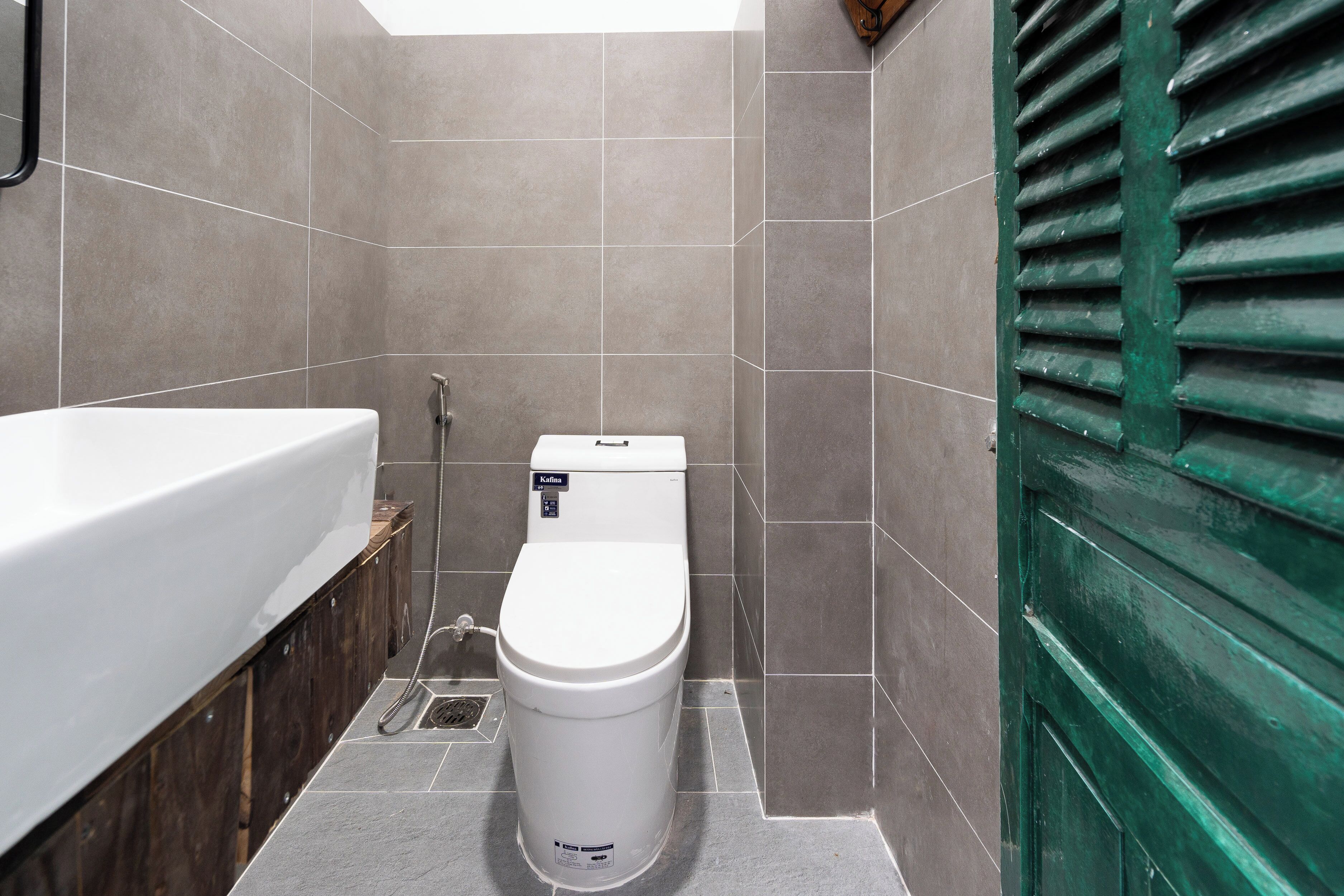 A bathroom with a white toilet, a bathtub, and a green door.