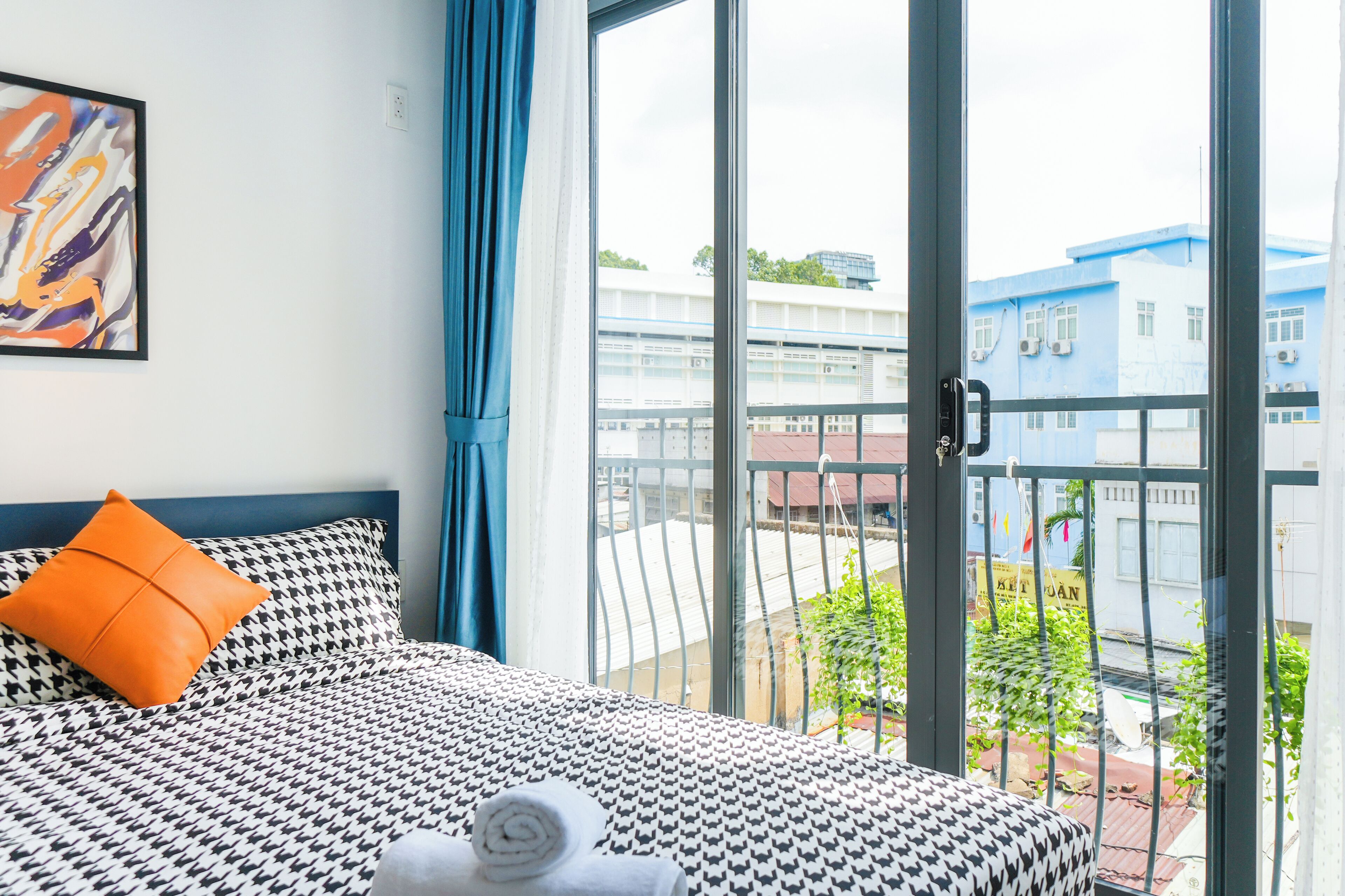 Camera d'albergo con un letto, una finestra vista sugli edifici e un balcone.