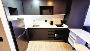 A modern kitchen with dark cabinetry, a white countertop, a built-in microwave, and a coffee maker.