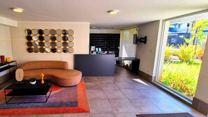 A modern living room with a sectional sofa, a coffee table, and a wall-mounted mirror display.