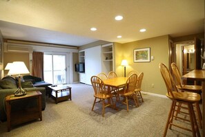 A living room with a dining table, chairs, a sofa, a TV, and a lamp. - Rivergreen 301, Lincoln (Lincoln)