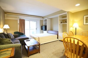 A hotel room with a sofa, a small table, a bed, a TV, and a dining area with chairs. - Rivergreen 301, Lincoln (Lincoln)