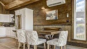 Una cocina con armarios blancos, una mesa de comedor de madera y dos sillas estampadas.