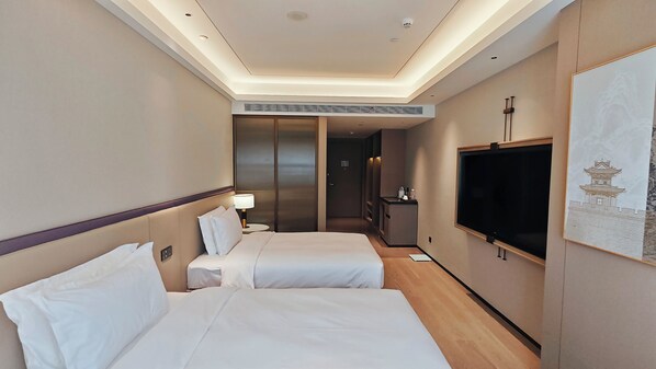 A hotel room with two beds, a TV, a desk, and a bathroom.