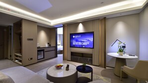 Ein modernes Wohnzimmer mit Flachbildfernseher, einer Couch, einem Couchtisch und einem kleinen Beistelltisch mit Pflanze.