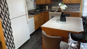Una cocina compacta con armarios de madera, un refrigerador blanco, una estufa y un comedor con una mesa y dos sillas.