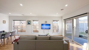 Ein modernes Wohnzimmer mit einer Couch, einem Esstisch, Stühlen und einem an der Wand befestigten Fernseher.