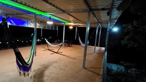 An outdoor covered area with a hammock, metal poles, and a concrete floor.