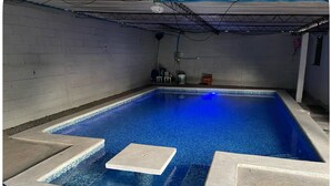 A rectangular indoor pool with a blue tint, surrounded by a concrete deck with a colorful edge.