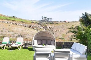 A patio with outdoor furniture, including a white cushioned chair and a round table with a dome-shaped cover. - Vista Golf 30 Salobre by VillaGranCanaria (Comarca Sur)