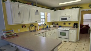 Una cocina con armarios blancos, una isla central, un microondas y una estufa.