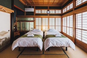 A traditional Japanese room with tatami flooring, two beds with white bedding, a shoji screen, and a wooden ceiling. - 20 minutes by car from Narita Airport  Spacious 1 / Narita Chiba (Narita)