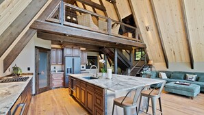 A spacious loft with a large kitchen, a dining area, and a living room with a high ceiling and exposed wooden beams. - Lake Views At Rockford Bay - The CDA-frame (Coeur d`Alene)