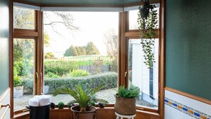 Een badkamer met een groot bad, houten vloeren en uitzicht op een tuin door een raam.